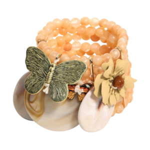 Maison Calix Giselle Bracelet Whimsical, romantic, and wonderfully unexpected, the Maison Calix Giselle Bracelet feels like a tiny enchanted garden wrapped around the wrist. Layers of softly glowing peach-toned beads create a lush stacked silhouette, adorned with an eclectic collection of sculptural butterflies, floral elements, and oversized shell-inspired charms. Giselle embodies the Maison Calix love of nature, nostalgia, and modern heirloom whimsy. A richly textured antique-inspired butterfly, miniature monarch-style accent, dimensional flower, and organic shell forms come together in a deliberately collected composition. Feminine without being precious and playful without losing sophistication, Giselle has the charm of a treasured piece discovered in a vintage jewelry box. Details Multi-strand statement bracelet Soft peach-toned round beads Layered wrap-style silhouette Large sculptural butterfly charm Miniature colorful butterfly accent Dimensional floral charm Organic shell-inspired drops Antique-inspired metal detailing Mixed natural and botanical motifs Warm sun-washed color palette Vintage charm-bracelet influence Maison Calix signature romantic whimsy Style Tip Maison Calix Giselle Bracelet